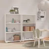 A bright and airy children's room with white shelving units filled with decorative items and storage baskets. Produktbild-Vorschau