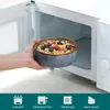 A hand is placing a bowl of cereal into a microwave. Náhled obrázku produktu