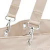 Close-up of the top of a beige fabric bag, showing the attachment points for straps. Voir les images du produit