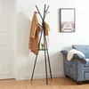 A coat rack with clothes and a hat is shown in a room with a sofa and a framed picture on the wall. Produktbild-Vorschau