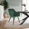 A green velvet dining chair is placed next to a black dining table in a well-lit room with a light green wall and wooden floor. Produktbild-Vorschau