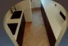 A modern kitchen with herringbone wood flooring, white countertops, and dark wood cabinets. Produktbild-Vorschau