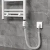 A white electric towel rail with a coiled power cord plugged into a wall socket, mounted on a gray tiled wall. Produktbild-Vorschau