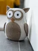 A stuffed owl doorstop sits on a gray surface next to a white wall. Anteprima dell’immagine prodotto