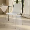 A white chair is placed next to a small glass-topped table with a linen cloth and a glass of water on it, in a room with sheer curtains and natural light. Produktbild-Vorschau
