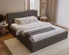 A bedroom scene with a large bed as the focal point, decorated with pillows and a throw blanket. The room has a modern, cozy aesthetic with soft lighting and textured walls. Náhľad obrázku produktu