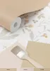 A roll of wallpaper with a floral pattern is shown, along with paint swatches and a paintbrush, suggesting a decorating project. Podgląd zdjęcia produktu