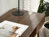 A close-up view of a wooden desk surface with a magazine and a lamp. Voir les images du produit