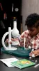 A young boy is using a microscope as part of a science experiment. Produktbild-Vorschau