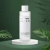 A bottle of Anua Heartleaf 77% Soothing Toner is displayed on a white circular stand, with lush green leaves and a dark green background. Náhľad obrázku produktu
