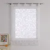 A white patterned curtain hangs in front of a window, with a framed picture and a candle on a nightstand to the left. Produktbild-Vorschau