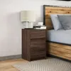 A bedside table with a lamp and books next to a bed. Náhled obrázku produktu