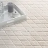 A close-up view of a cream-colored rug with a diamond pattern, featuring a white tray with a gray candle and a white apple. Anteprima dell’immagine prodotto