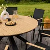 An outdoor dining set with a round table and chairs on a wooden deck, surrounded by grass. Produktbild-Vorschau