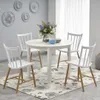 A white round dining table with four white chairs around it, set in a dining room with decorative wall plates and a floral rug. Náhľad obrázku produktu