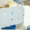 Close-up of a light blue organizer with pencils and a stapler on a shelf next to a white blanket and a patterned pillow. Produktbild-Vorschau