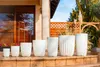 A row of white planters of varying sizes are displayed on a porch or patio. Anteprima dell’immagine prodotto