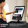 A woman is using a treadmill with a large screen displaying streaming service options. Produktbild-Vorschau