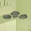 A collection of glass food storage containers with gray lids are arranged on a light green countertop. Náhled obrázku produktu
