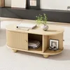 A modern, oval-shaped coffee table with slatted cabinet doors and open shelving, placed on a textured rug. Voir les images du produit