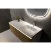 A modern bathroom vanity with a white countertop and sink, featuring a wood-grain cabinet and integrated LED lighting. A faucet is running water into the sink. Produktbild-Vorschau