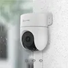 A white security camera mounted on a textured wall, with a background suggesting rain and different weather conditions. Produktbild-Vorschau