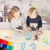 Two young girls are sitting at a table and doing a craft project with colorful beads and templates. Produktbild-Vorschau