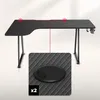 A black L-shaped gaming desk with a close-up inset of a cable grommet. Podgląd zdjęcia produktu