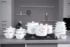 A collection of white enamel pots with lavender designs, arranged on a kitchen countertop and stovetop. Náhľad obrázku produktu