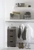 A closet or storage area with shelves, a drawer unit, and clothes on hangers. Voir les images du produit