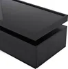 A close-up, angled view of a modern black coffee table with one drawer slightly ajar, showcasing its high-gloss finish and minimalist design. Produktbild-Vorschau