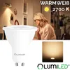 A woman is working at a desk with a lamp in the background, and a product image of an LED bulb is in the foreground. Produktbild-Vorschau