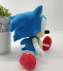 A plush toy of Sonic the Hedgehog is shown sitting on a white surface next to a potted plant. Produktbild-Vorschau