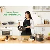 A woman is cooking in a modern kitchen with a set of pots and pans. Anteprima dell’immagine prodotto