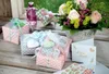 A collection of gift-wrapped presents, a bouquet of flowers, and greeting cards arranged on a wooden surface. Voir les images du produit