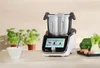 A multi-functional kitchen robot is displayed on a countertop with fresh vegetables and a bowl of ingredients nearby. Náhled obrázku produktu
