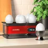 A red egg cooker with several eggs in it, placed on a kitchen counter next to a plant. Podgląd zdjęcia produktu