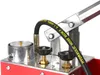 A close-up view of a hydraulic pressure testing pump, showing its components like the pressure gauge, hose, and control knobs. Náhľad obrázku produktu