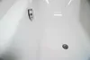 A close-up view of a white bathtub with a chrome drain and a chrome fixture. Produktbild-Vorschau