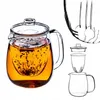 A glass teapot filled with amber-colored tea and loose tea leaves inside a glass infuser, shown against a white background. To the right, a diagram illustrates the teapot's components. Anteprima dell’immagine prodotto