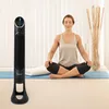 A woman meditates in a room with a tower fan. Podgląd zdjęcia produktu