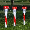 Three candy cane-shaped LED solar lights are placed in the grass, with snowflakes falling around them. Anteprima dell’immagine prodotto