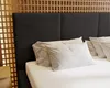A bed with a black upholstered headboard and white pillows. Náhled obrázku produktu