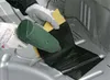 A person wearing gloves is using a heat gun to apply a black sound-deadening material to a metal surface. Produktbild-Vorschau