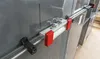 A close-up view of a clamp mechanism attached to a metal rail, likely for industrial or workshop use. Náhľad obrázku produktu