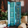 Two decorative book-shaped advent calendars are displayed in a festive setting with greenery and rustic materials. Náhled obrázku produktu