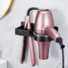 A wall-mounted holder for a hairdryer and a flat iron, made of black metal, against a marble-patterned wall. Produktbild-Vorschau