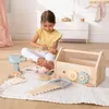 A young girl is playing with a wooden toy toolbox and tools on a rug in a room. Produktbild-Vorschau