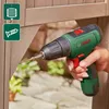 A person is using a green Bosch cordless drill to screw into a wooden structure outdoors. Produktbild-Vorschau