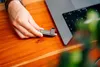A person's hand is inserting a USB drive into a laptop. Náhľad obrázku produktu